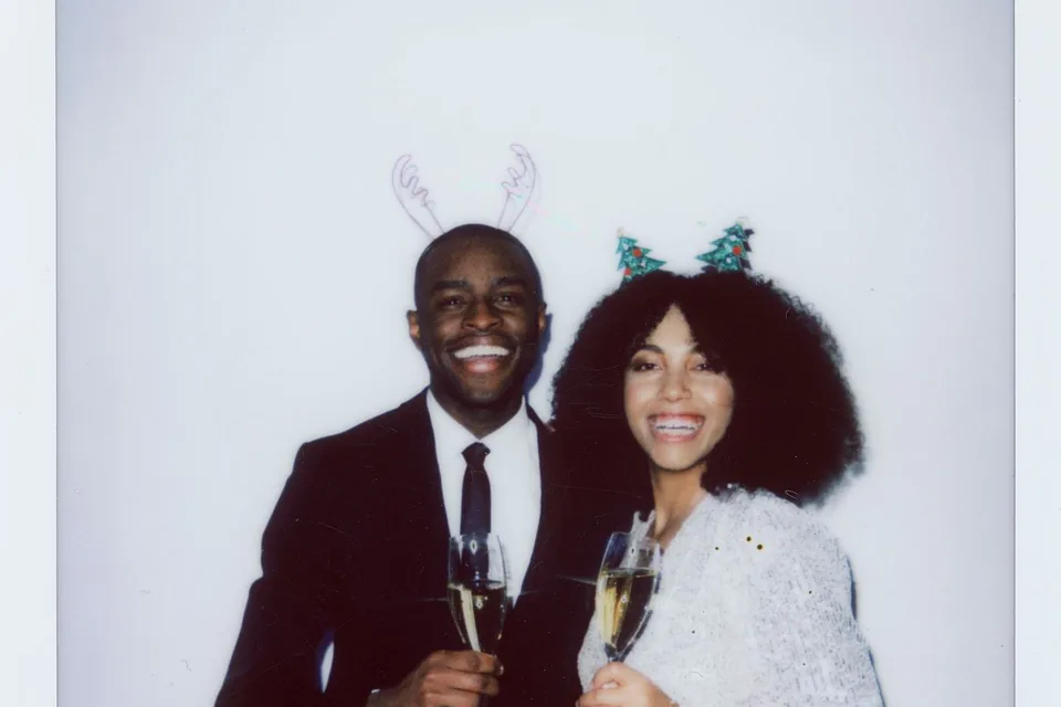 Couple souriant au champagne sur un tirage de photobooth, avec des accessoires de fête