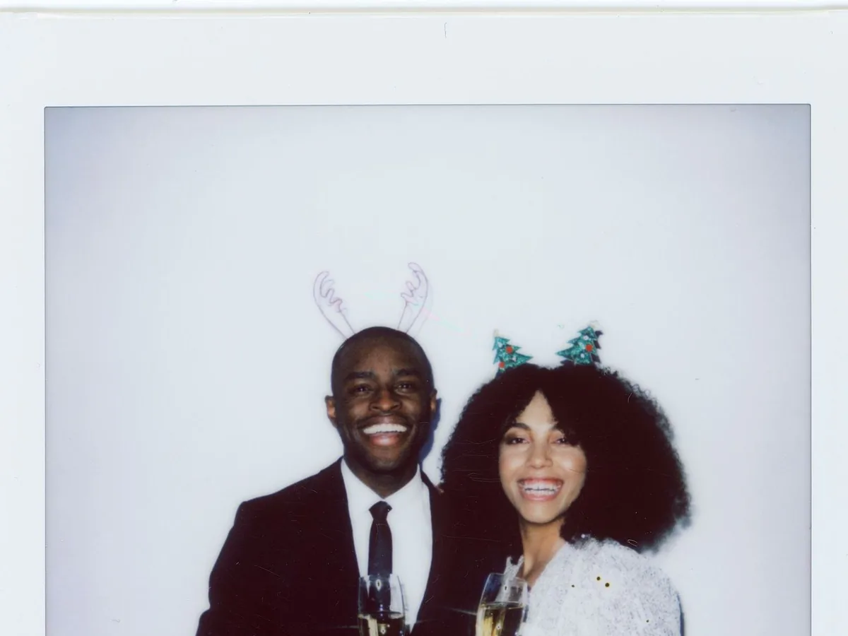 Couple souriant au champagne avec des accessoires de fête, tirage façon polaroid d’un photobooth