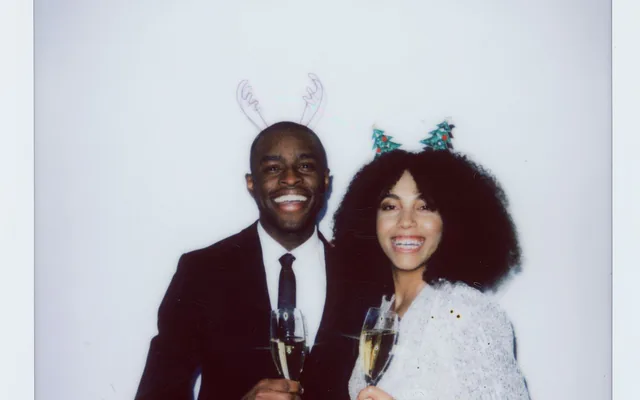 Couple souriant au champagne avec des accessoires de fête, tirage façon polaroid d’un photobooth
