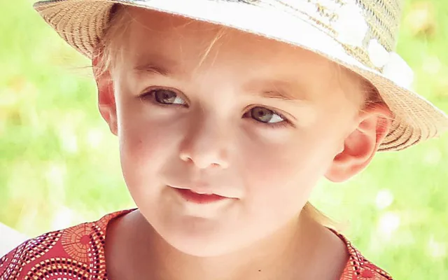 Petite fille au chapeau de paille, portrait en gros plan dans la lumière d’été