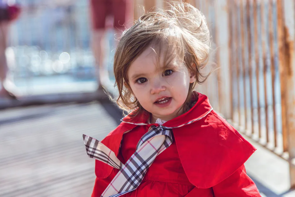 Petite fille souriante en cape rouge, le port de Marseille en arrière-plan