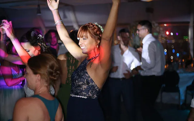 Invitée qui danse bras levés sous les lumières colorées d’une soirée de mariage à Marseille