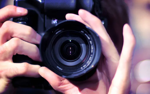 Main d’un photographe tenant un objectif, en gros plan