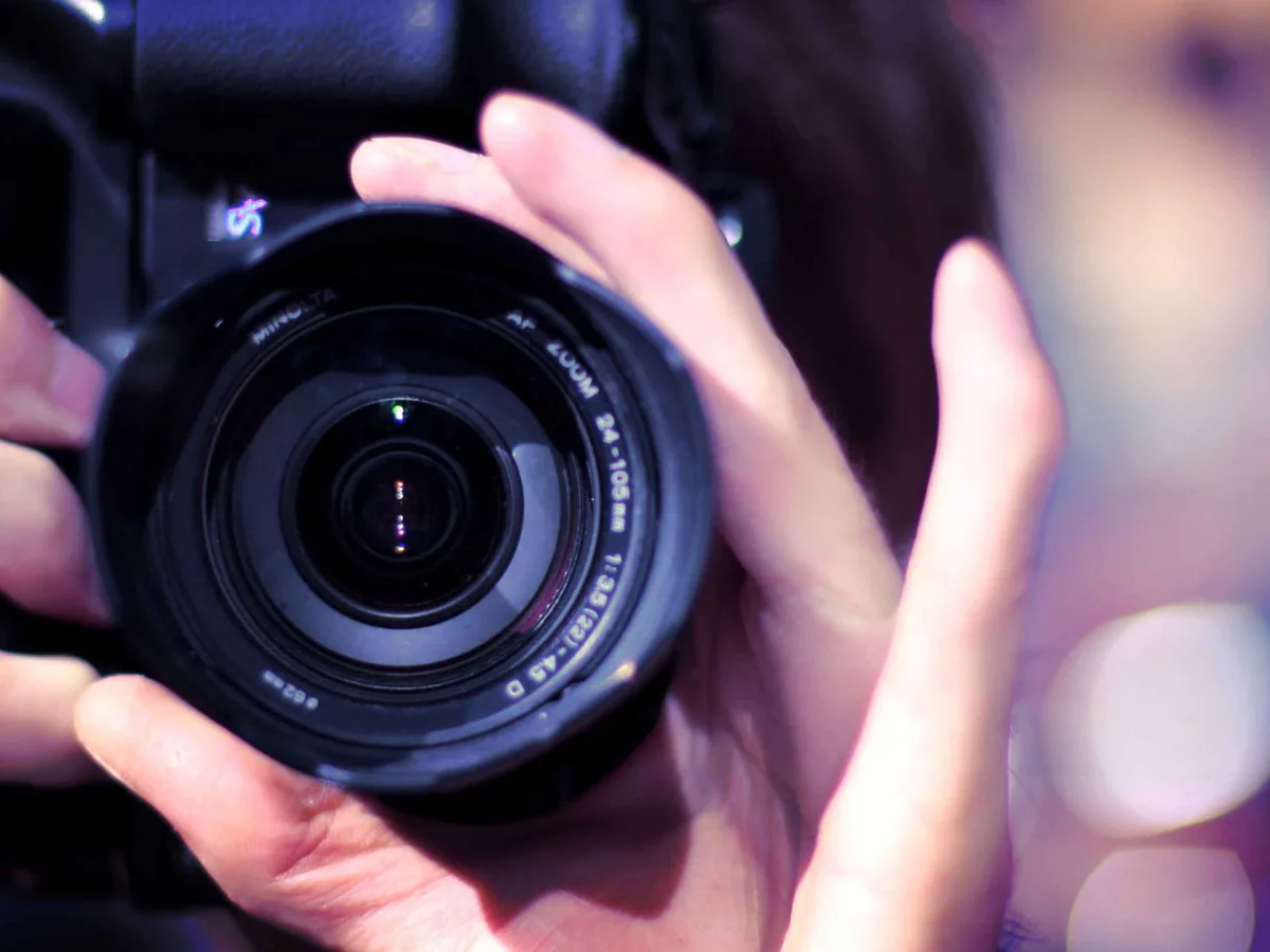 Main d’un photographe tenant un objectif, en gros plan