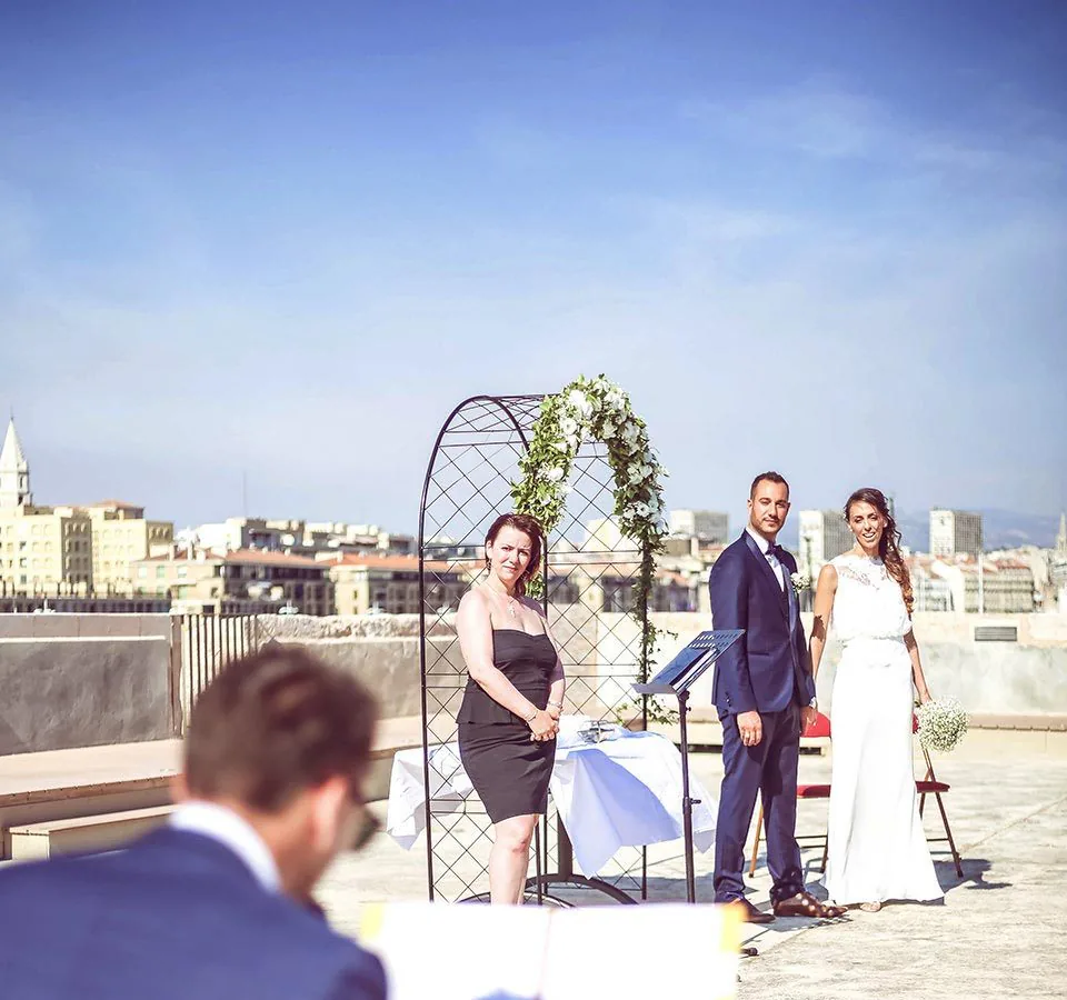 Pianiste devant une assemblée lors d’une cérémonie en plein air, avec Marseille en arrière-plan