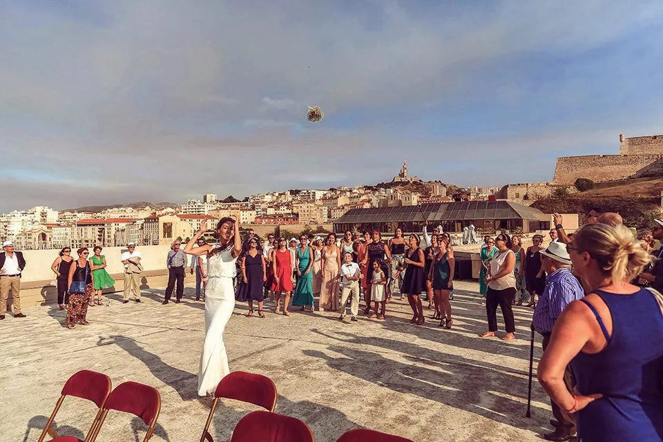 Lancer de bouquet sur un toit-terrasse avec le panorama de Marseille au soir