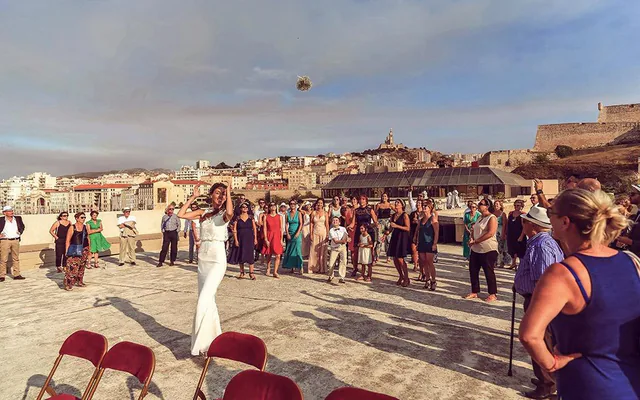 Lancer de bouquet sur un toit-terrasse avec le panorama de Marseille au soir