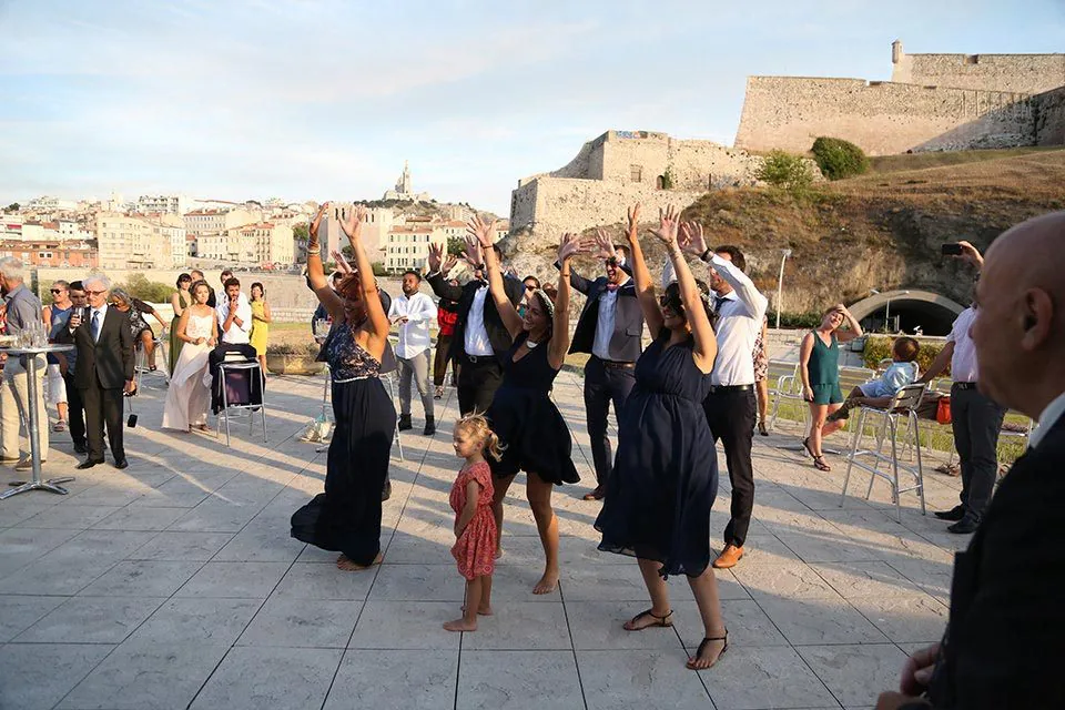 Invités qui dansent en plein air devant le fort et Notre-Dame de la Garde, à Marseille