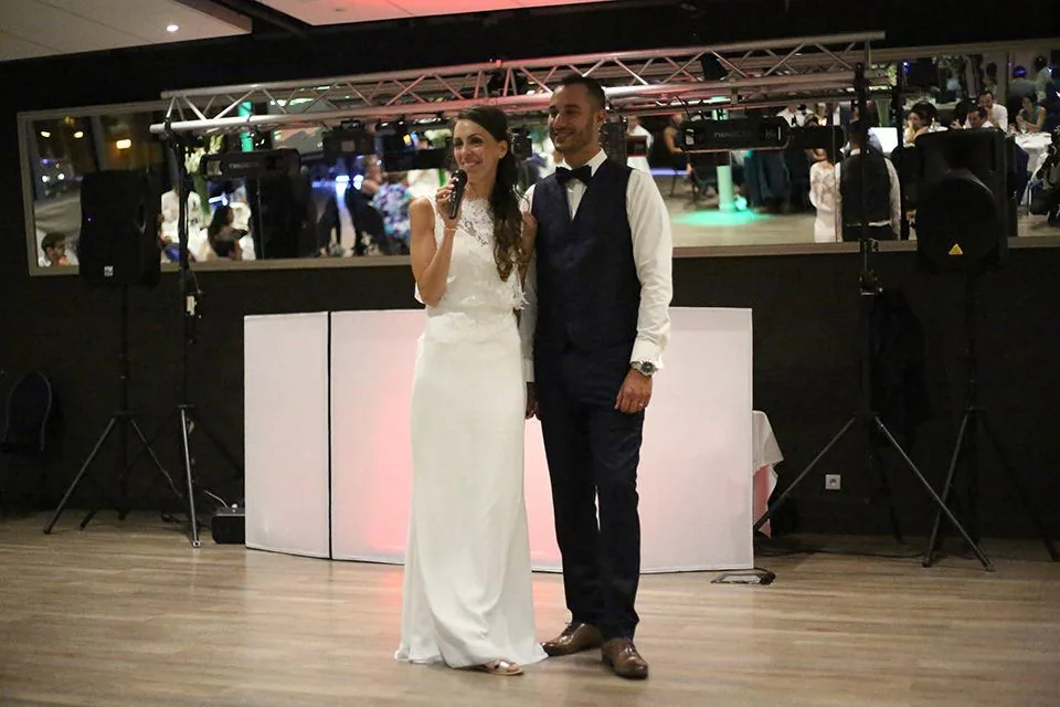 Les mariés au micro pendant leur discours, dans la salle de soirée