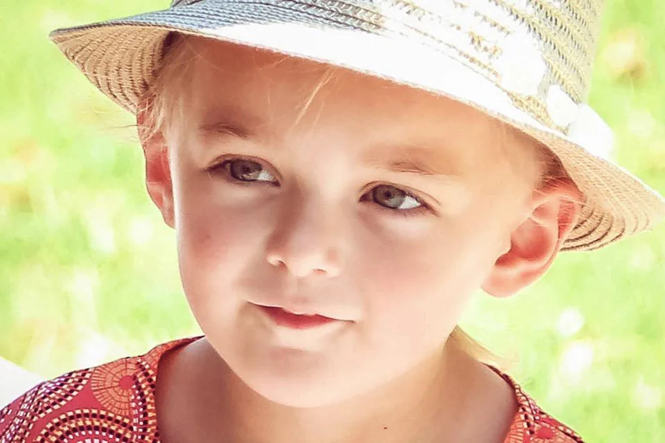 Gros plan d’une petite fille au chapeau de paille, photographiée lors d’un mariage