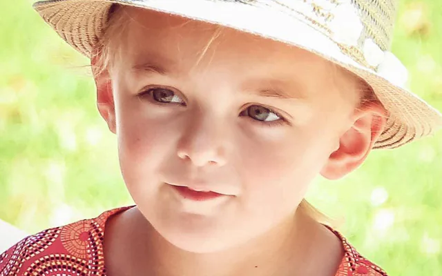 Gros plan d’une petite fille au chapeau de paille, photographiée lors d’un mariage