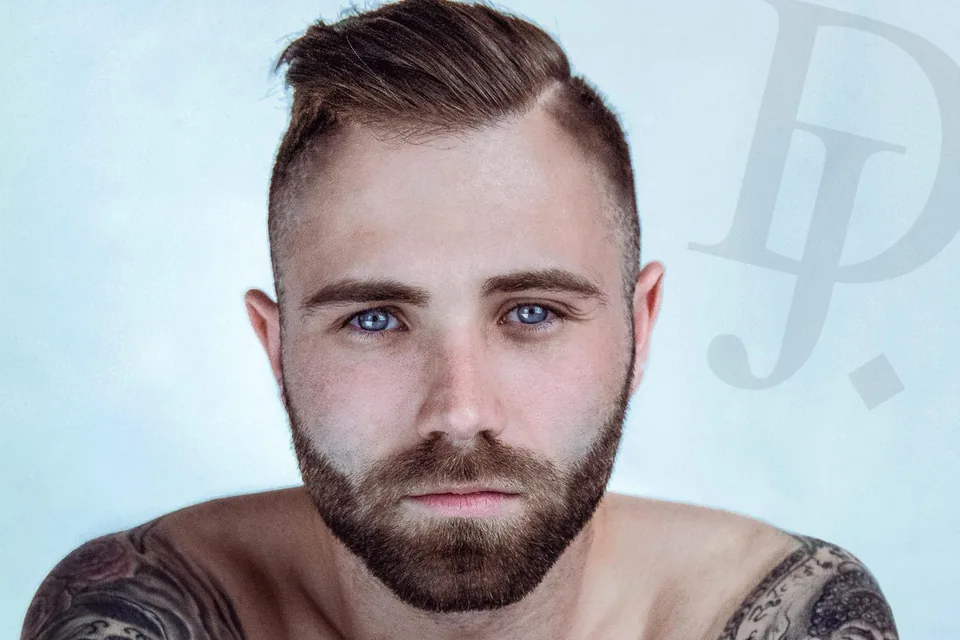 Portrait d’un homme tatoué, bras croisés, sur fond blanc en studio à Marseille