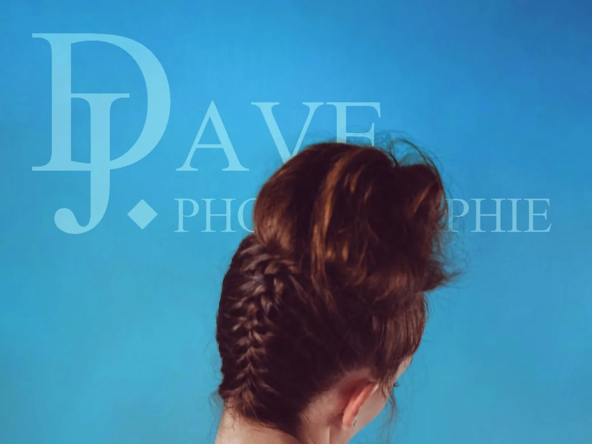 Femme de dos en chemise fleurie, chignon tressé, sur fond bleu au studio photo à Marseille