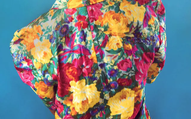 Femme de dos en chemise fleurie, chignon tressé, sur fond bleu au studio photo à Marseille
