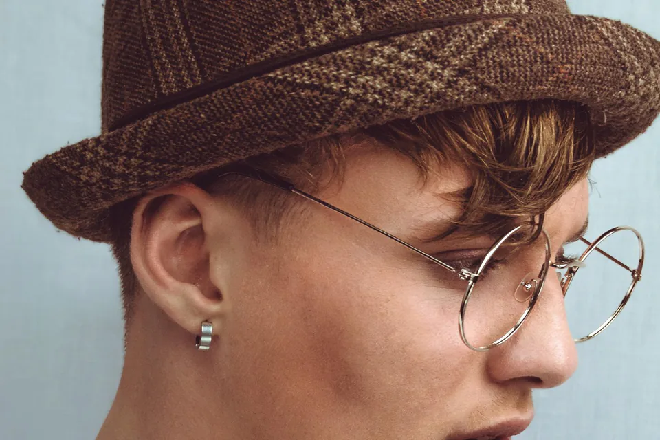 Portrait d’une jeune personne à lunettes rondes et casquette sur fond blanc, au studio à Marseille