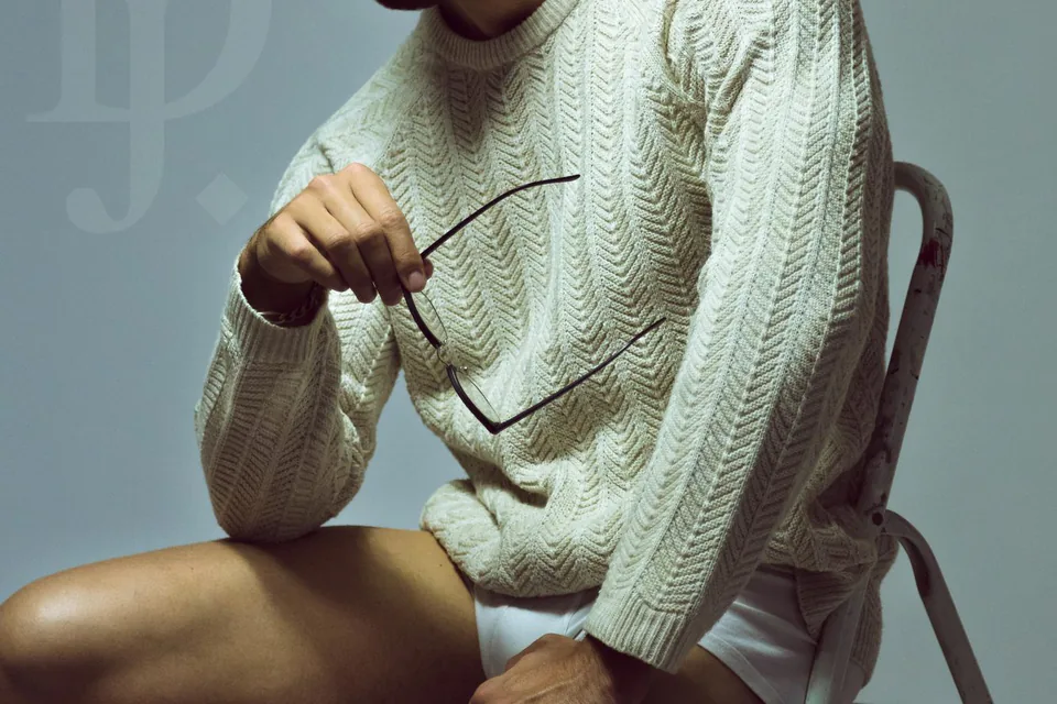 Homme en pull crème assis, lunettes à la main, portrait au studio à Marseille