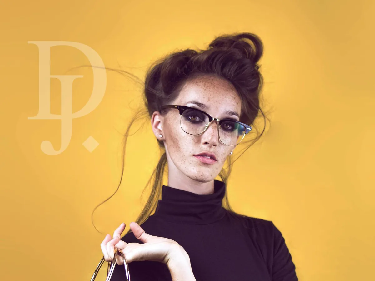 Femme à lunettes, col roulé noir et sac jaune, photographiée sur fond jaune au studio à Marseille