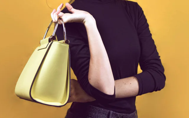 Femme à lunettes, col roulé noir et sac jaune, photographiée sur fond jaune au studio à Marseille