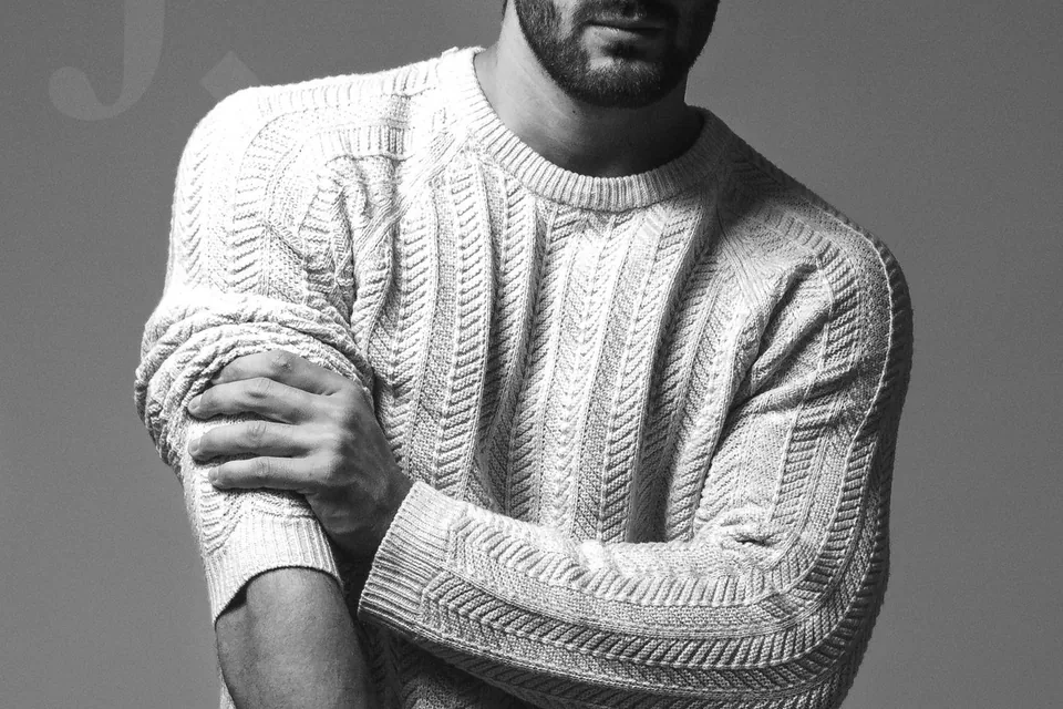 Homme en pull blanc, bras croisés, portrait en noir et blanc réalisé au studio à Marseille