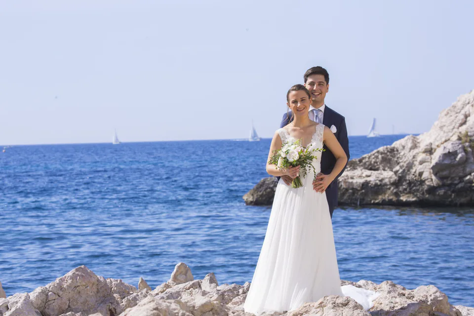 Couple de mariés debout sur les rochers face à la mer, dans une calanque de Marseille