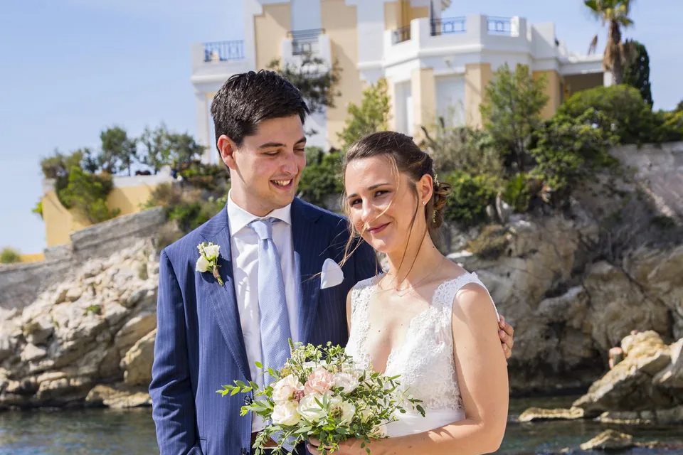 Couple de mariés en pied dans une calanque, rochers blancs et ciel bleu, près de Marseille