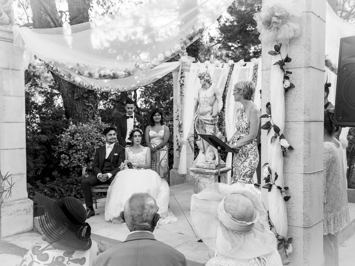 Cérémonie laïque de mariage en noir et blanc, l’assistance sous une arche de voilages, en Provence
