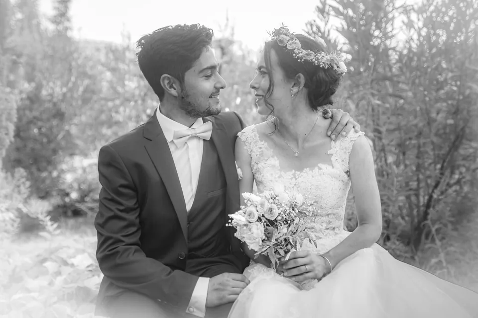 Le même couple de mariés assis dans un jardin, développé en noir et blanc